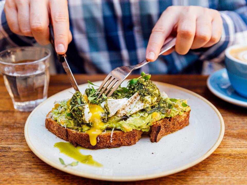 A man eating avocado toast with a poached egg.