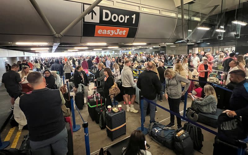 Passengers queue outside Terminal 1 after an overnight power cut led to disruptions and cancellations at Manchester Airport in Manchester