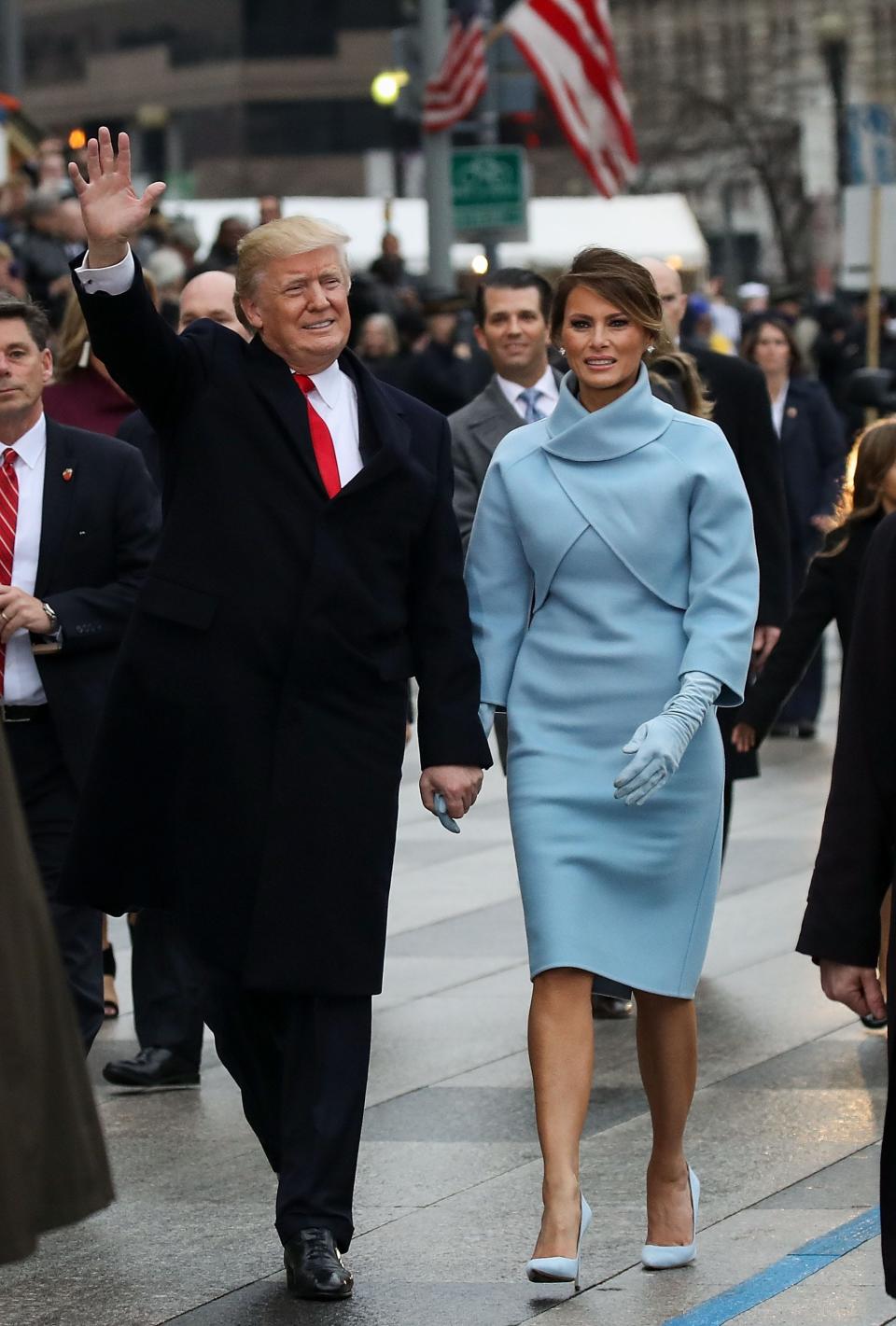 Donald and Melania in a powder blue dress, jacket-shawl, gloves, and matching heels.