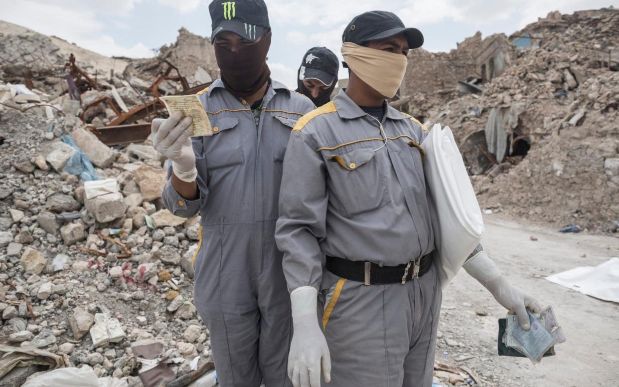 A team of body collectors look at ID cards found in the rubble of Mosul's Old City in April 2018 - Sam Tarling