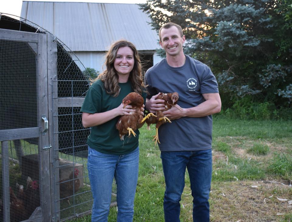 Adam Paynter and his wife, Amanda, each hold one of their egg layer chickens at Paynter Family Organic Farm in 2023. The couple recently moved their poultry stock to their home in Shelby.