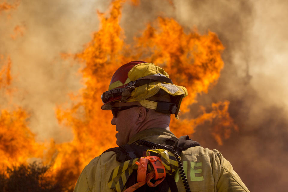 A firefighter watches the Apple Fire in Cherry Valley, Calif., Saturday, Aug. 1, 2020. A wildfire northwest of Palm Springs flared up Saturday afternoon, prompting authorities to issue new evacuation orders as firefighters fought the blaze in triple-degree heat.(AP Photo/Ringo H.W. Chiu)