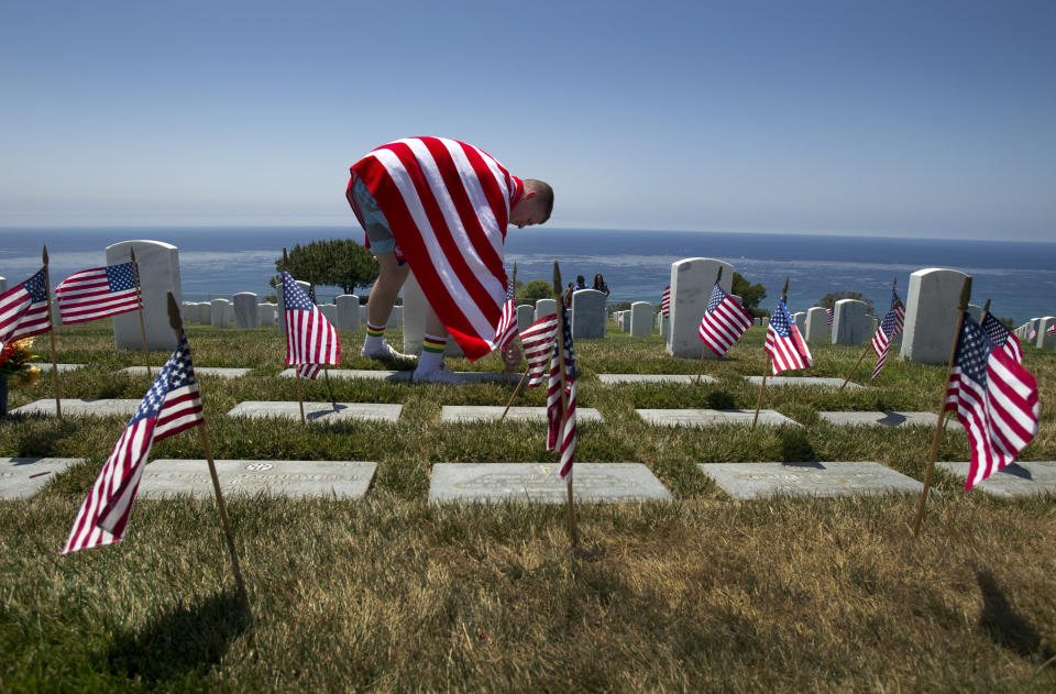 Lance Corporal Cameron Davis, of Marine Corps Air Station Miramar, wraps himself in an American flag towel as he props up fallen flags while paying his respects to fellow service men and women at Rosecrans National Cemetery in San Diego on Sunday, May 25, 2014.