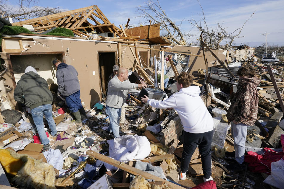 People help retrieve items from a destroyed home Saturday, Dec. 11, 2021, in Mayfield, Ky. Tornadoes and severe weather caused catastrophic damage across several states Friday, killing multiple people overnight. (AP Photo/Mark Humphrey)