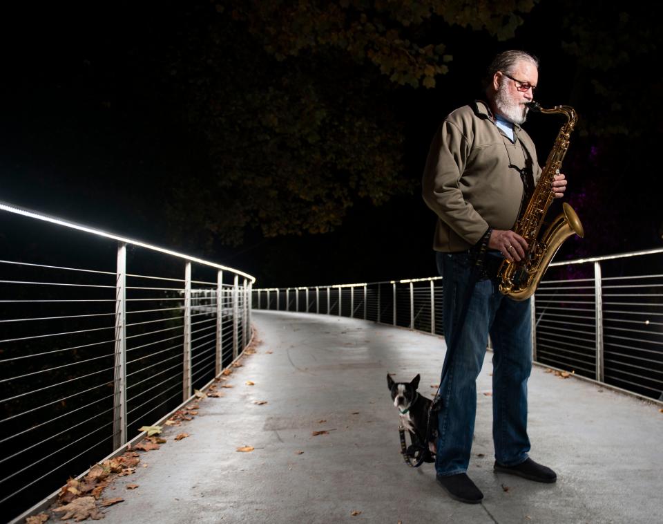 John Sterling of Greenville, plays his saxaphone along side his dog Poppy in downtown Greenville, Tuesday, November 16 2021.  