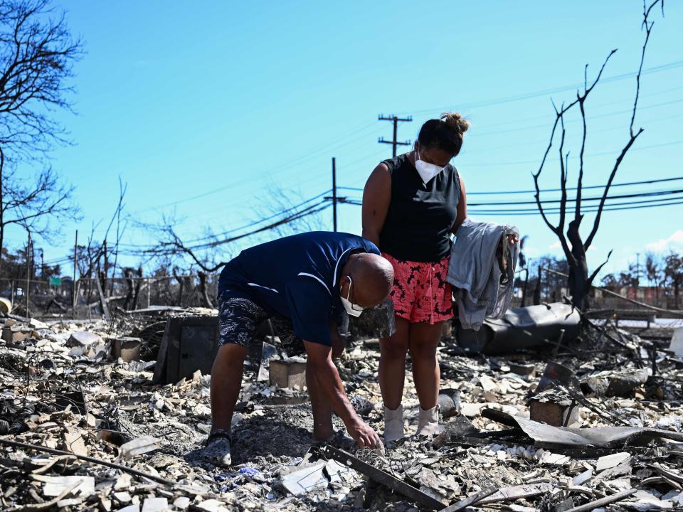 Two Maui residents look through the ashes of their family home after the wildfires this week.
