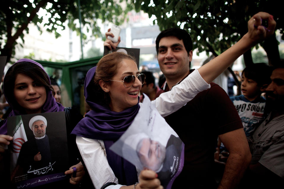 Iranians celebrate the victory of moderate presidential candidate Hassan Rowhani (portrait) in the Islamic Republic's presidential elections in downtown Tehran on June 15, 2013. (BEHROUZ MEHRI/AFP/Getty Images)