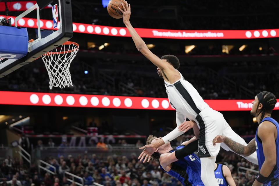 Orlando Magic center Moritz Wagner, bottom left, is charged with a foul as he tries to stop San Antonio Spurs center Victor Wembanyama, top, from making a basket during the second half of an NBA basketball game, Thursday, Feb. 8, 2024, in Orlando, Fla. (AP Photo/John Raoux)