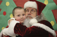 Santa Claus poses with a child at the Trapper School in Nuiqsut, Alaska, on Tuesday, Nov. 29, 2002. Operation Santa Claus, the Alaska National Guard's outreach program, attempts to bring Santa and Mrs. Claus and gifts to children in two or three Alaska Native villages each year, including Nuiqsut in 2022. (AP Photo/Mark Thiessen)