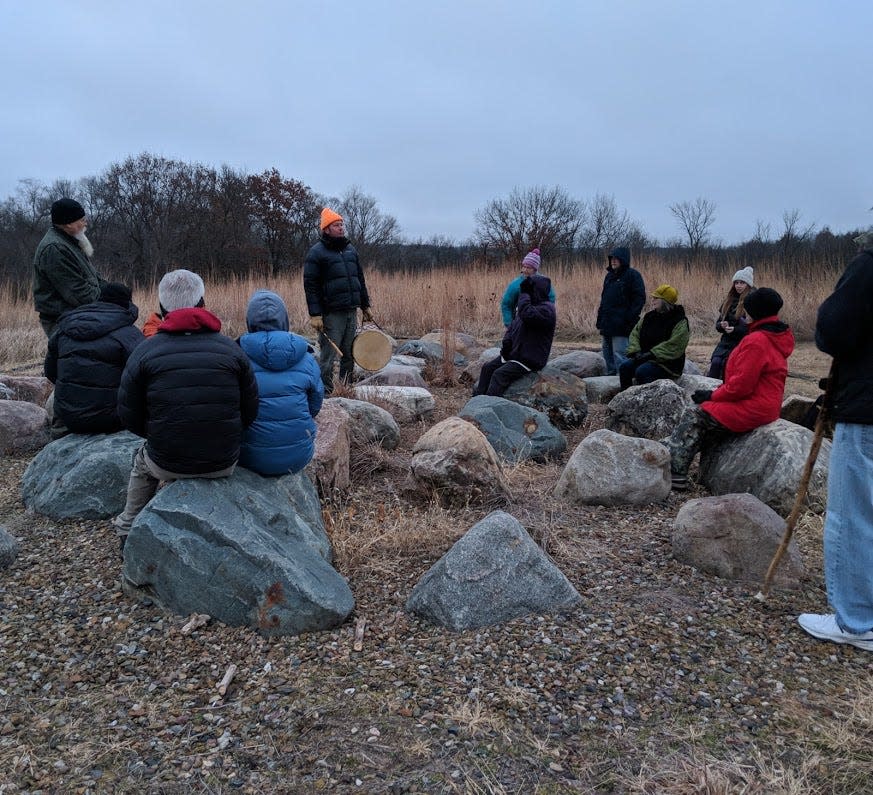 Dallas County naturalists Chris Adkins, far left, and Mike Havlik, center, lead a group at Hanging Rock Conservation Area near Redfield in celebrating a past winter solstice.