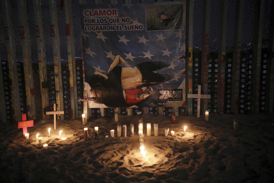 Candles are placed next to the border fence that separates Mexico from the United States, in memory of migrants who have died during their journey toward the U.S., in Tijuana, Mexico, late Saturday, June 29, 2019. On the border fence hangs a cartoon depiction of a news photograph of the bodies of Salvadoran migrant Óscar Alberto Martínez Ramírez and his daughter Valeria, who drowned on Sunday, June 23 on the banks of the Rio Grande between Matamoros, Mexico, and Brownsville, Texas. (AP Photo/Emilio Espejel)