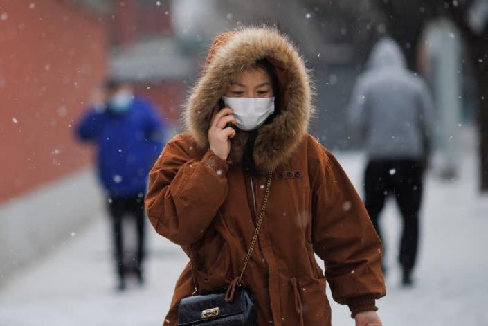 A person wears a face mask while walking on a snowy morning as the coronavirus disease (COVID-19) continues in Beijing