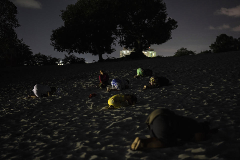 Mujeres prostradas para rezar en una zona del sistema de dunas de Abaete, en una parte elevada que los evangélicos han empezado a llamar Montaña Sagrada, en Salvador, Brasil, el viernes 16 de septiembre de 2022. Grupos evangélicos se congregan en el enorme sistema de dunas de Abaete desde hace 25 años, pero especialmente ahora, cuando miles de personas acuden cada semana para cantar, rezar y en ocasiones alcanzar estado de trance. Algunos escriben plegarias en trozos de papel que luego queman. (AP Foto/Rodrigo Abd)