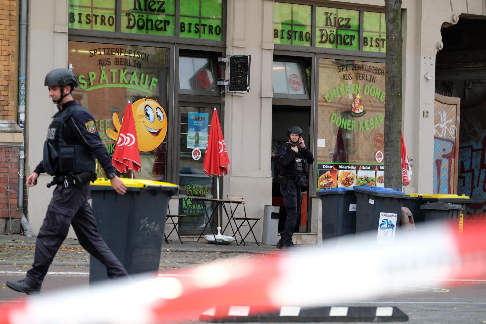 A police officer walks in front of a kebab grill in Halle, Germany, Wednesday, Oct. 9, 2019. A gunman fired several shots on Wednesday in the German city of Halle. Police say a person has been arrested after a shooting that left two people dead. (Sebastian Willnow/dpa via AP)