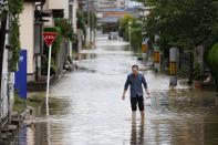 A man walks through a flooded road following heavy rain in Omuta, Fukuoka prefecture, southern Japan Tuesday, July 7, 2020. Floodwaters flowed down streets in southern Japanese towns hit by heavy rains. (Juntaro Yokoyama/Kyodo News via AP)