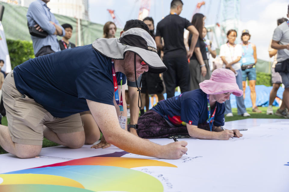 Participants sign on the quilt at the AIDS Quilt Memorial Ceremony, ahead of the Gay Games in Hong Kong, Saturday, Nov. 4, 2023. The first Gay Games in Asia are fostering hopes for wider LGBTQ+ inclusion in the regional financial hub, following recent court wins in favor of equality for same-sex couples and transgender people. (AP Photo/Chan Long Hei)
