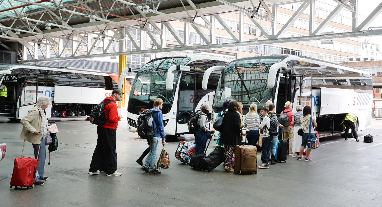 People board a National Express coach at the Victoria Coach Station, in central London.
