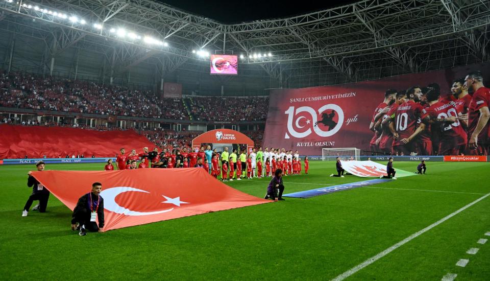 <span>The Turkey players sing their national anthem alongside a banner celebrating the 100th anniversary of the formation of Turkish Republic, before the Euro 2024 qualifier against Wales.</span><span>Photograph: Tullio Puglia/Uefa/Getty Images</span>