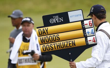 Tiger Woods of the U.S. (L) walks past the scoreboard as he leaves the 18th green during the first round of the British Open golf championship on the Old Course in St. Andrews, Scotland, July 16, 2015. REUTERS/Russell Cheyne