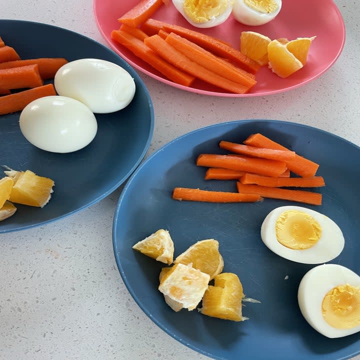 hardboiled eggs, carrots, and oranges on plates