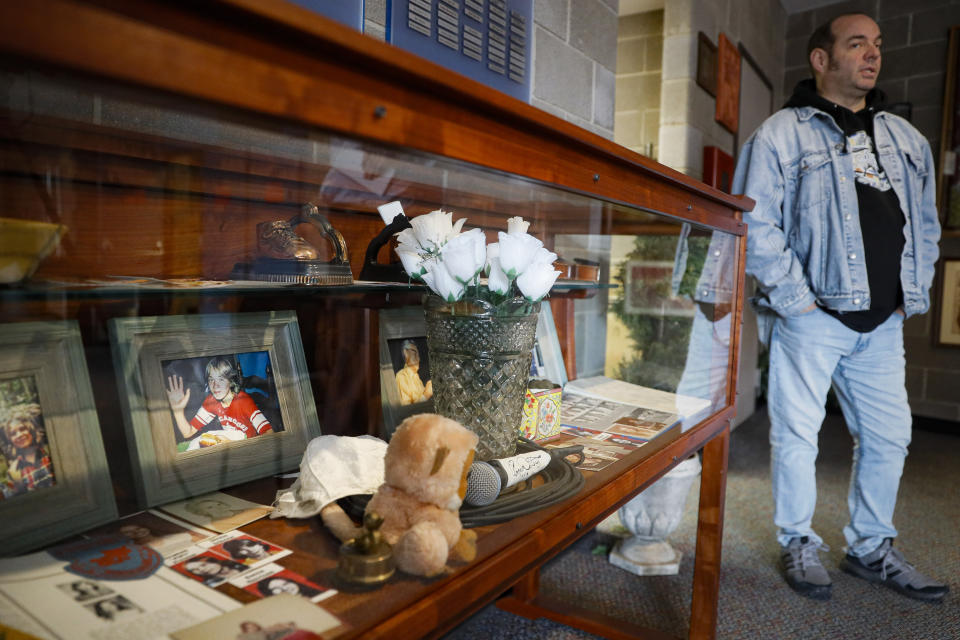 In this Thursday, Nov. 21, 2019 photo, Fred Wittenbaum, of the P.E.M. scholarship that memorializes the three Finneytown students killed in a stampede at The Who's Dec. 3, 1979 concert, stands beside a cabinet of mementoes honoring the dead at the Finneytown High School secondary campus, in Finneytown, Ohio. Tragedy four decades ago linked the British rock band to the small suburban city in Ohio. In recent years, members of the community and the band have bonded through a project to memorialize the teens. (AP Photo/John Minchillo)