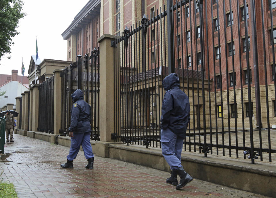 South African policemen walk outside the court building were Oscar Pistorius will arrive later for his trial, at the high court in Pretoria, South Africa, Monday, March 3, 2014. Pistorius is charged with premeditated murder for the shooting death of his girlfriend, Reeva Steenkamp, on Valentine's Day in 2013. (AP Photo/Schalk van Zuydam)