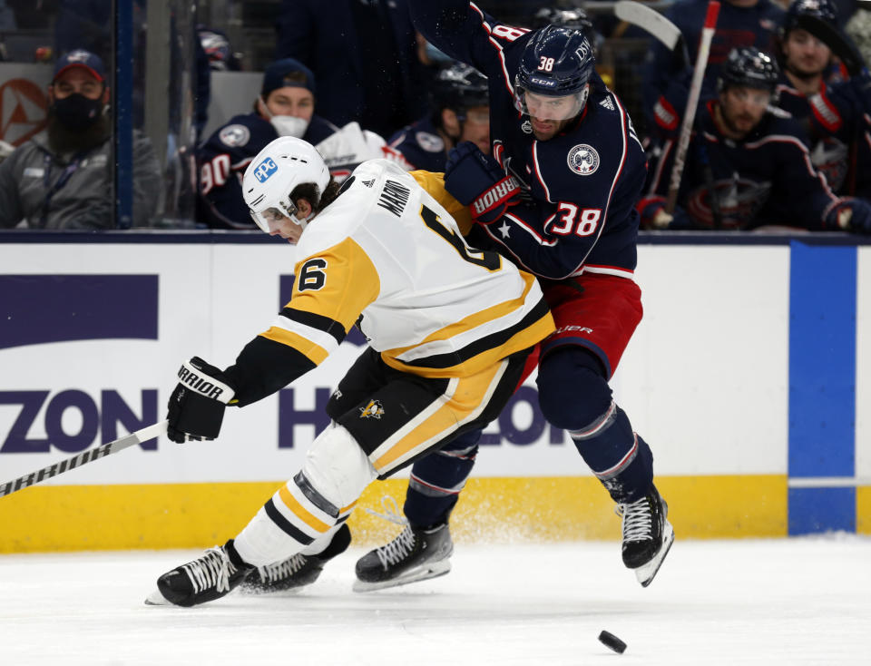 Columbus Blue Jackets forward Boone Jenner, right, chases the puck behind Pittsburgh Penguins defenseman John Marino during the second period of an NHL hockey game in Columbus, Ohio, Friday, Jan. 21, 2022. (AP Photo/Paul Vernon)