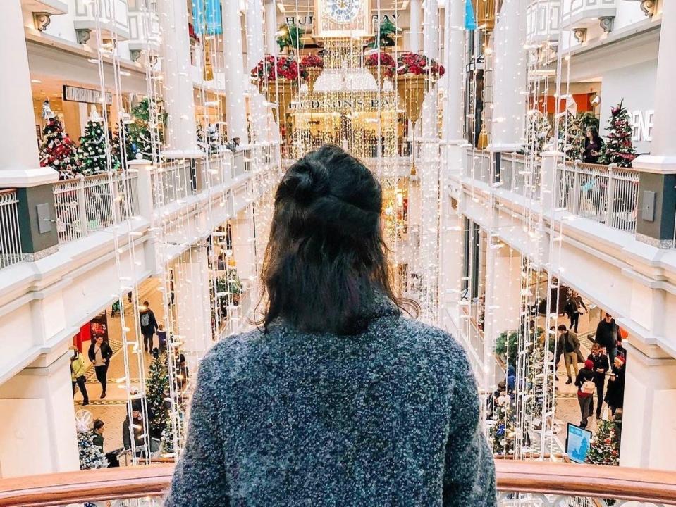 simone standing looking over a balcony of decorations and Christmas trees at the festival of trees in victoria canada