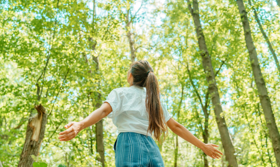 Woman breathing clean air in nature forest. Fresh outdoor woods, wellness healthy lifestyle concept.