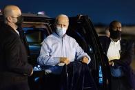 Democratic presidential candidate former Vice President Joe Biden holds up his wet suit coat and looks at members of the media before boarding his plane at Tampa International Airport in Tampa, Fla., Thursday, Oct. 29, 2020, to return home to Wilmington, Del., after attending rallies. Biden was caught in a sudden downpour during his final rally of the day. (AP Photo/Andrew Harnik)