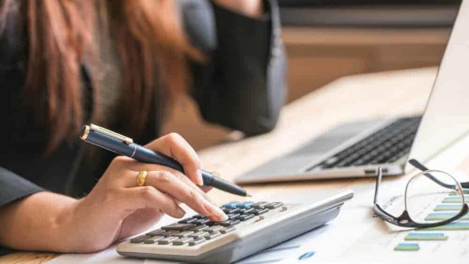 Woman calculating figures next to a laptop