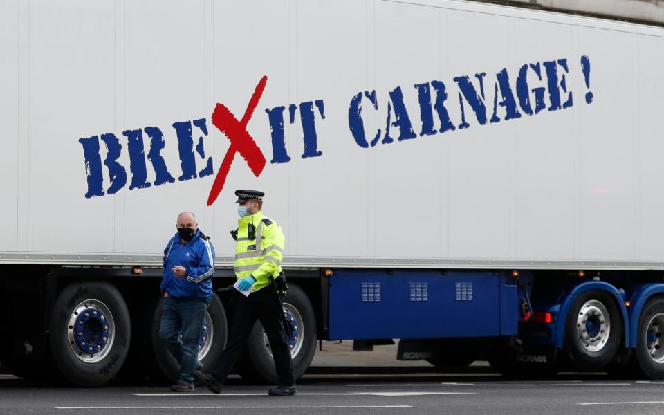 A policeman escorts the driver of a shellfish export truck as he is stopped for an unnecessary journey - AP