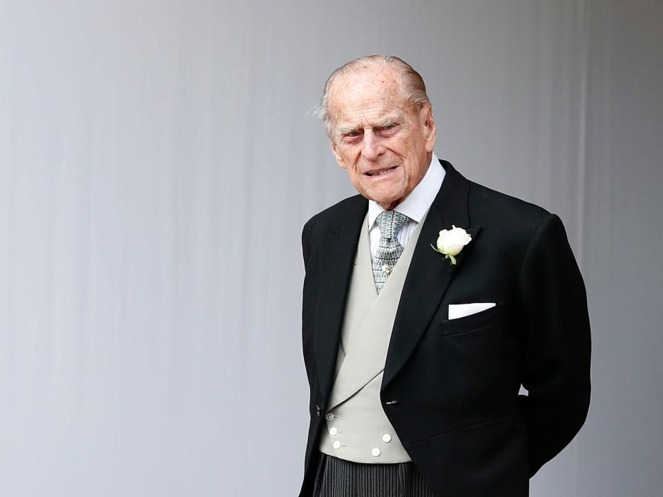 Prince Philip, Duke of Edinburgh, pictured standing alone in a black suit and gray vest and tie in front of a white background at the wedding of Princess Eugenie of York to Jack Brooksbank at St. George's Chapel on October 12, 2018 in Windsor, England.