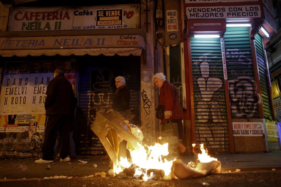 People pass a fire during a protest in Madrid November 4, 2013. Spain's labor unions called for an indefinite strike from Tuesday in Spain's capital for the street cleaning and park maintenance sectors in protest against announced layoffs that could affect around a thousand municipal workers, according to local media. (REUTERS/Juan Medina)