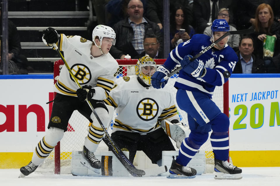Toronto Maple Leafs center John Tavares (91) tries to control the puck as Boston Bruins defenseman Mason Lohrei (6) defends and Bruins goaltender Jeremy Swayman (1) looks on during first-period NHL hockey game action in Toronto, Monday, March 4, 2024. (Frank Gunn/The Canadian Press via AP)