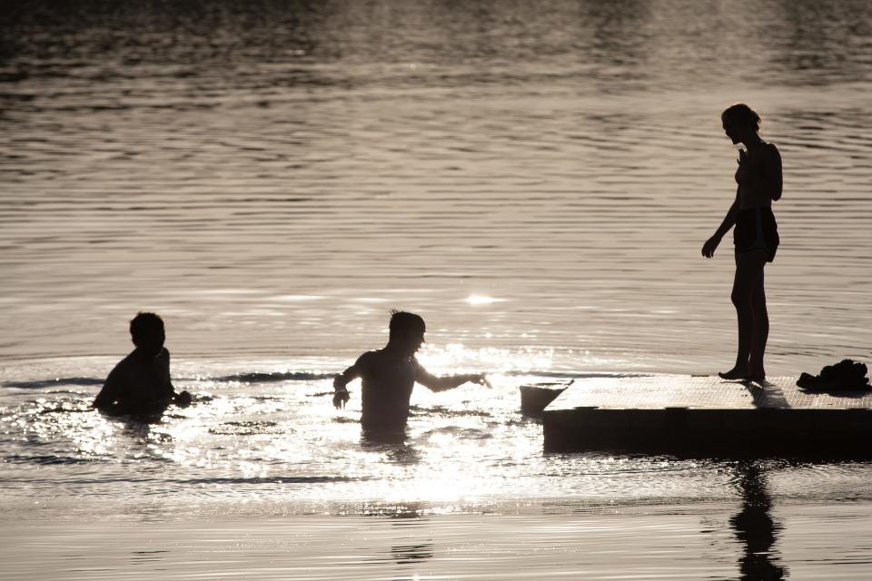 From left to right, Garreth Palmer, Coby Lowe and Carly Moon cool off from the high temperatures by taking a dip off Wednesday evening off a dock at Lake Shawnee.