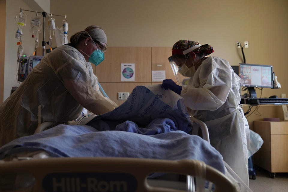 FILE - In this Dec. 22, 2020, file photo, registered nurses Robin Gooding, left, and Johanna Ortiz treat a COVID-19 patient at Providence Holy Cross Medical Center in the Mission Hills section of Los Angeles. Coronavirus deaths in the U.S. hit another one-day high on Tuesday, Jan. 12, 2021, at over 4,300 with the country’s attention focused largely on the fallout from the deadly uprising at the Capitol. (AP Photo/Jae C. Hong, File)