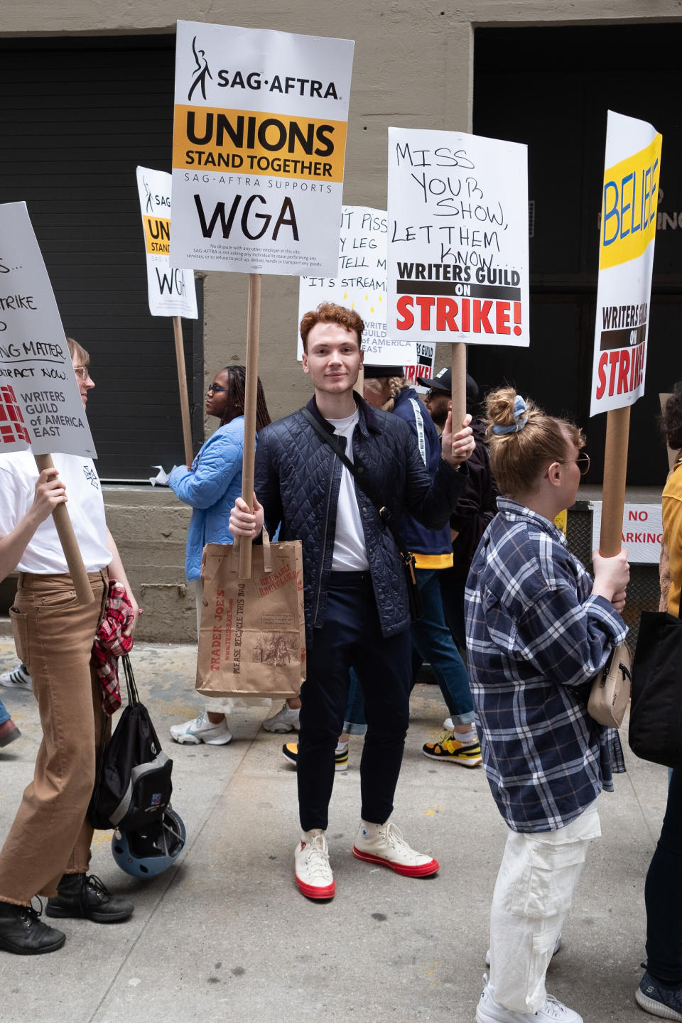person standing on the street holding a Trader Joe's bag at the WGA strike