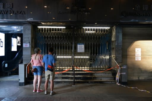 Tourists look at the closed and vandalised Admiralty metro station -- increased vandalism in Hong Kong has shocked a city known for its stability