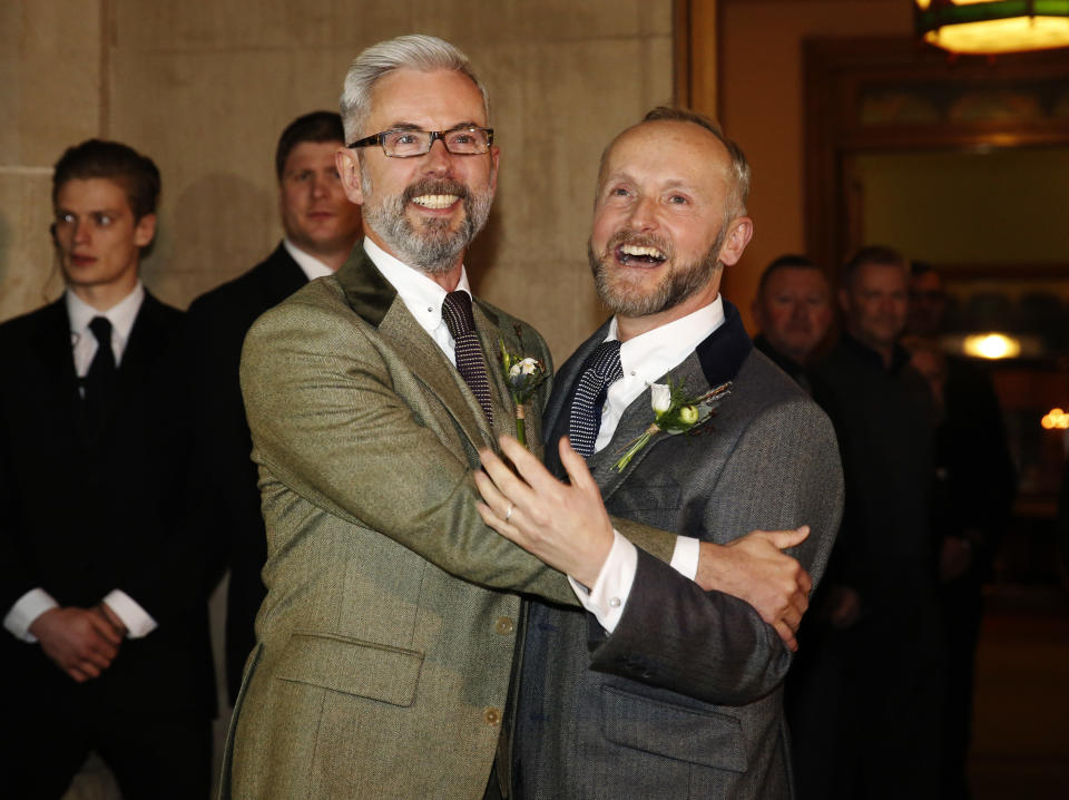 Gay couple Andrew Wale (L) and Neil Allard reacts to crowds, friends, family and the press after marrying in the first same-sex wedding in Brighton, at the Royal Pavilion in southern England March 29, 2014. Saturday will be the first day gay couples will be allowed to tie the knot in England and Wales after the government legalised same-sex marriage last July. Wale and Allard are the first out of five same-sex couples tying the knot in Brighton on Saturday. REUTERS/Luke MacGregor (BRITAIN - Tags: SOCIETY)