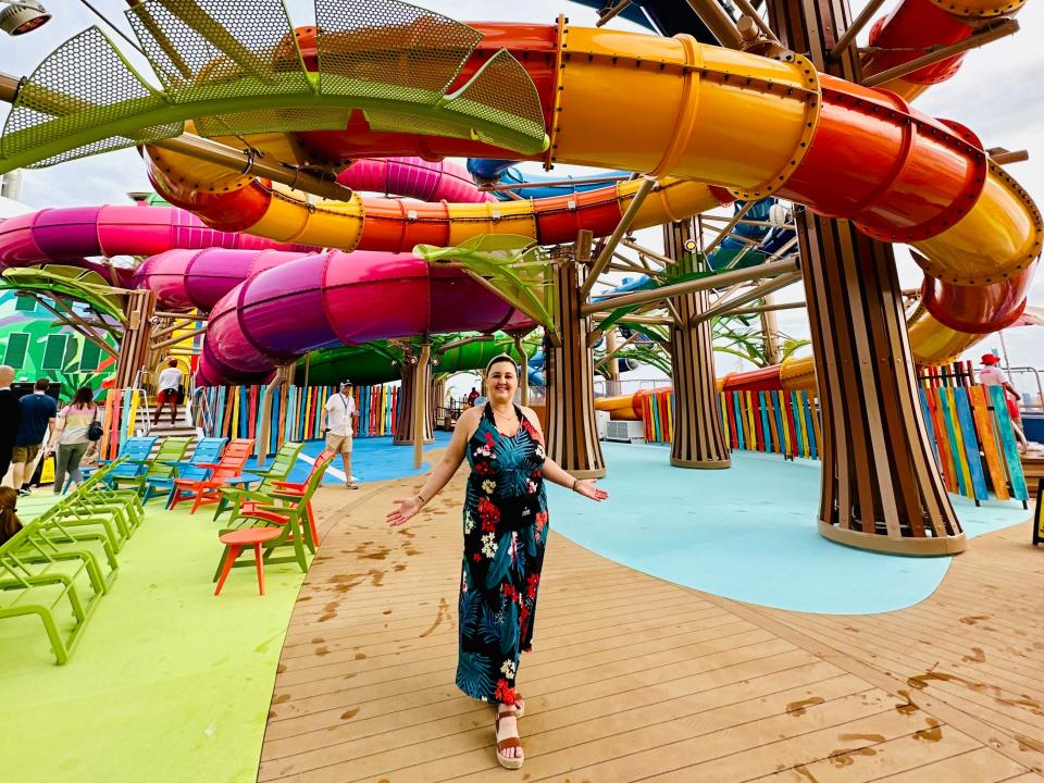 Carly poses underneath multiple water slides on a cruise deck.