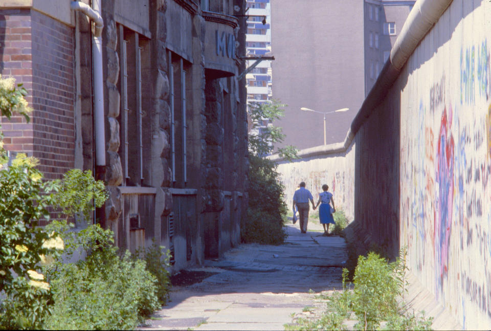 <p>Dos personas pasean junto al muro de Berlín en una foto de 1986. (Photo by Thierlein/ullstein bild via Getty Images)</p> 