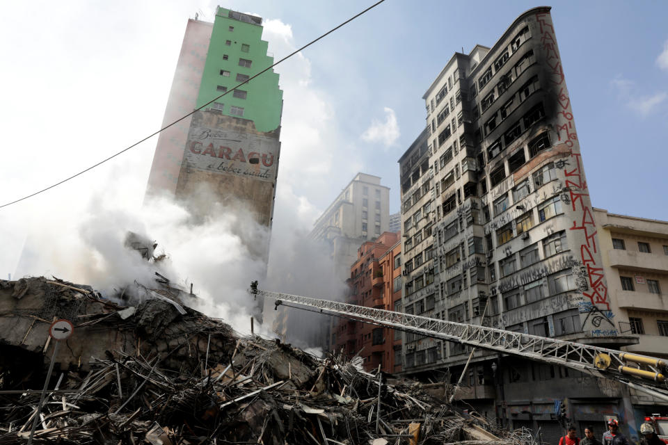 Firefighters extinguish the charred ruins of the abandoned office building. Source: Reuters