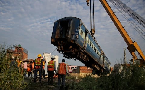 Workers remove the an upturned coach - Credit: AP Photo/Altaf Qadri