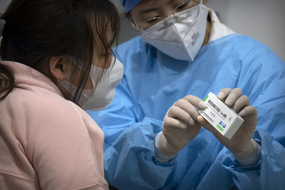 A medical worker shows a person the packaging for a Sinopharm vaccine at a vaccination facility in Beijing on Jan. 15, 2021. Two vaccines made by China’s Sinopharm appear to be safe and effective against COVID-19, according to a study published in a medical journal. Scientists have been waiting for more details about the two vaccines, even though they already are being used in many countries and one recently won the backing of the World Health Organization. (AP Photo/Mark Schiefelbein)