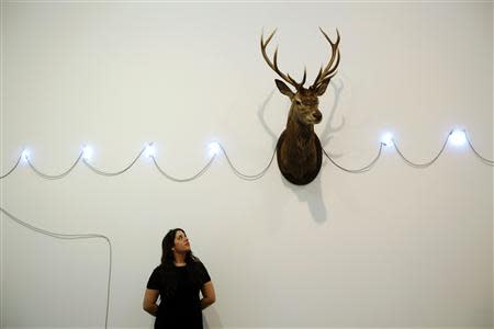 A Christie's employee poses with Mario Merz's untitled artwork at Christie's Mayfair gallery in London February 5, 2014. REUTERS/Luke MacGregor