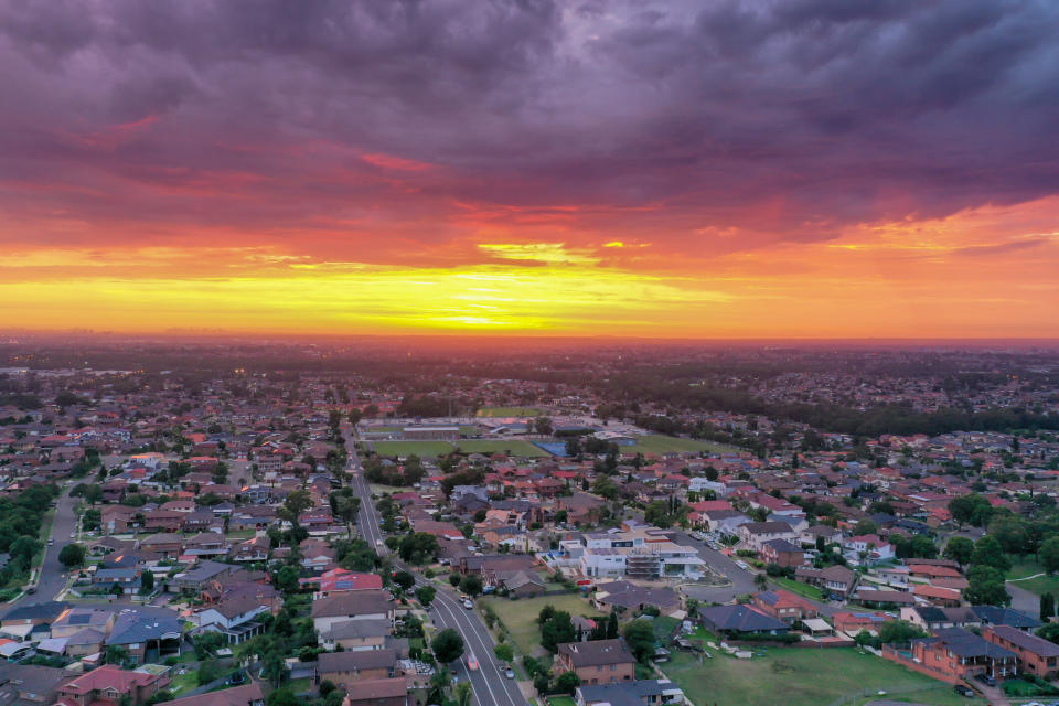 A sun rises above residential suburbs in Australia.