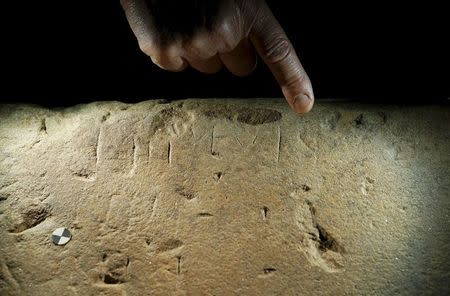 A restorer points to an inscription on an Etruscan stele in a restoration centre in Florence, Italy, April 20, 2016. REUTERS/Remo Casilli