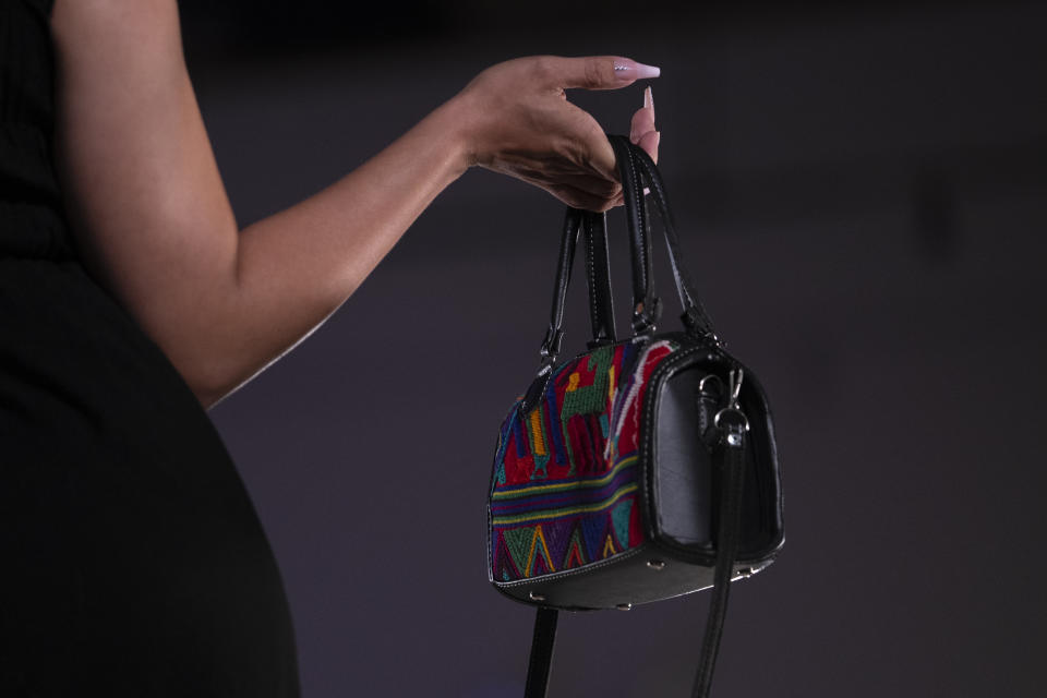 A model displays a purse during a fashion show featuring Guatemalan textiles, Friday, May 12, 2023, in Brownsville, Texas. A Guatemala-born designer combined indigenous weaving technique, modern clothing design and colorful history from her native country came together on a recent weekend on on a runway showcase. The fashion show offered a taste of not only Elena De León's artistic vision, but of the work by mothers living in the U.S. or back in their country to support their families. (AP Photo/Julio Cortez)
