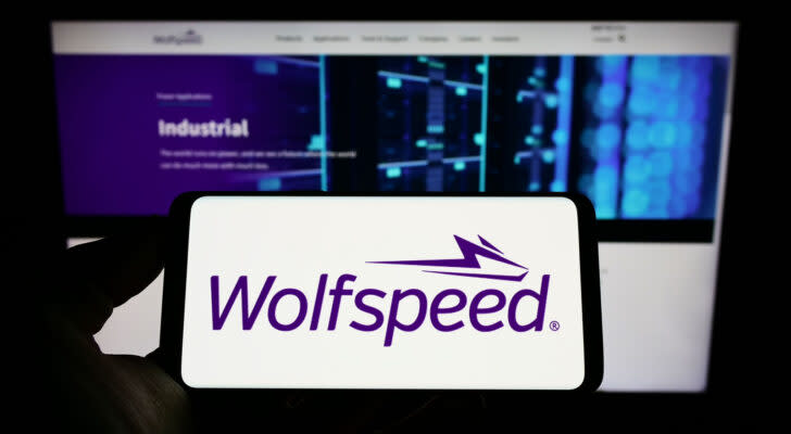 WOLF stock: Person holding smartphone with logo of US semiconductor company Wolfspeed Inc. on screen in front of website. Focus on phone display.